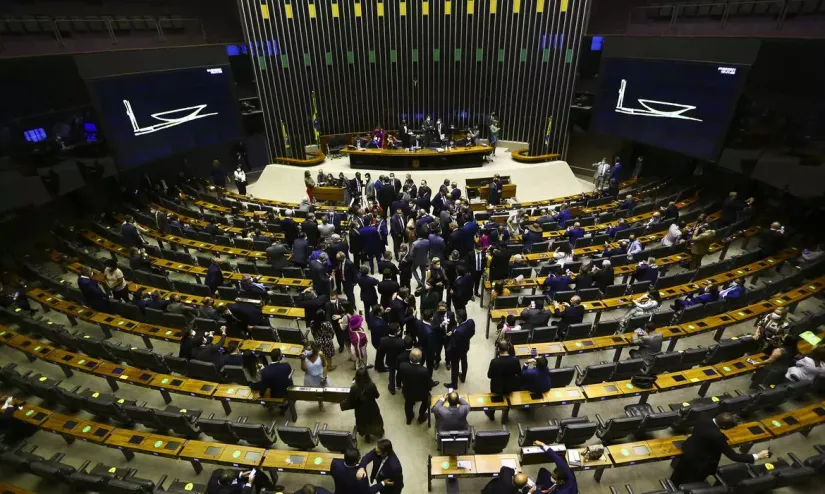 Foto da câmara dos deputados, com deputados circulando no ambiente