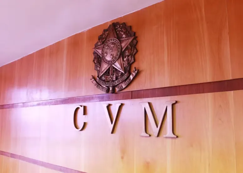 Logo da CVM e brasão da República em uma parede de madeira, representando a autarquia.