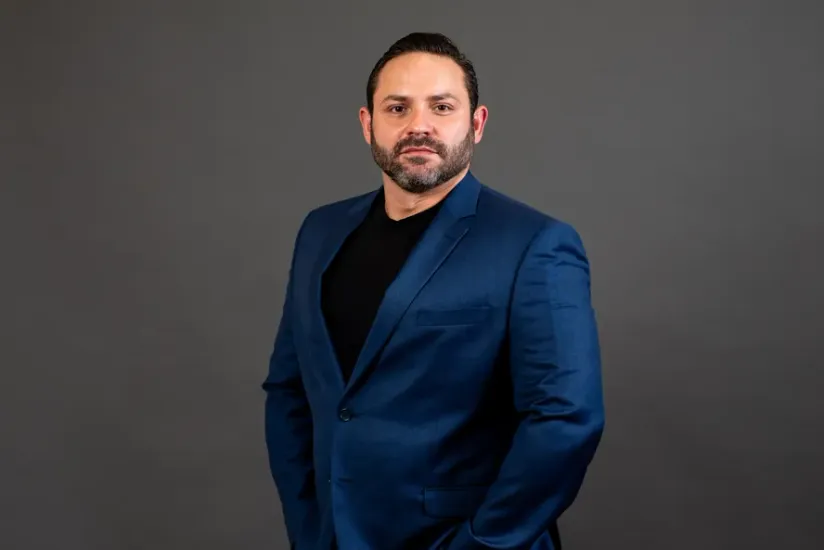 Retrato de Bernardo Srur. Ele está vestindo um blazer azul, o seu olhar tem uma expressão séria.